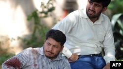 A blood-covered UN employee sits outside his office after a suicide blast in Islamabad on October 5.