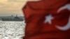 A Turkish flag flies on a ferry as Russian warship, the BSF Saratov 150, sails through the Bosphorus off Istanbul en route from the Black Sea to the eastern Mediterranean late last year. 