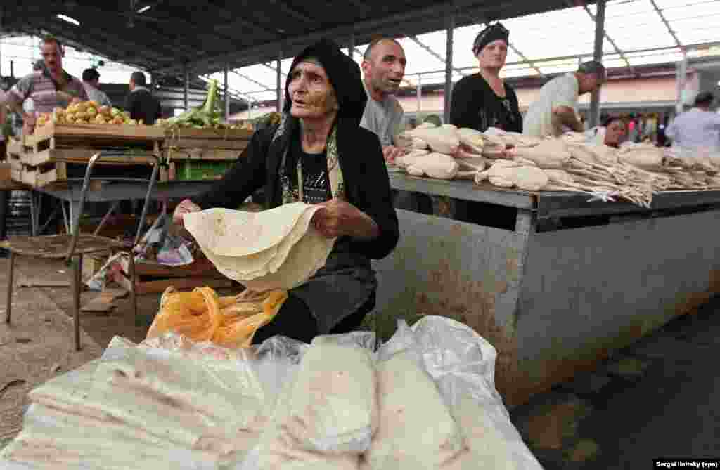 An elderly Azerbaijani woman selling bread in the central market of Baku. As towers and stadiums have grown up around them, little has changed for the people on the street.&nbsp; &nbsp;