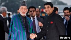 Afghan President Hamid Karzai (left) shakes hands with Indian Minister of State for Home Affairs R.P.N Singh on his arrival in New Delhi on December 12.