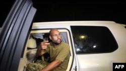 Saif al-Islam Qaddafi appears in front of supporters and journalists at his father's residential complex in Tripoli in late February.